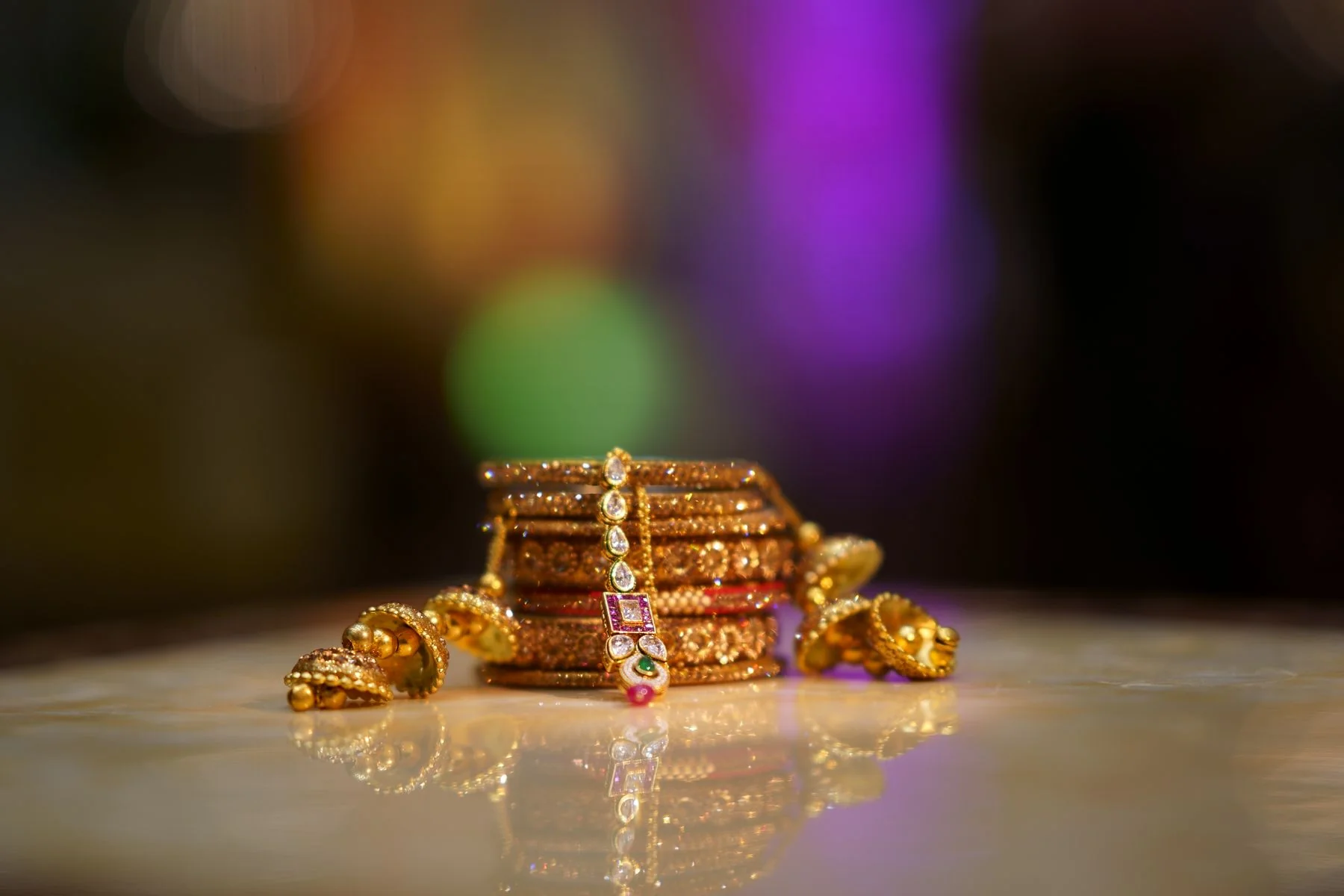 Ornate gold bangles and earrings on polished marble in warm light